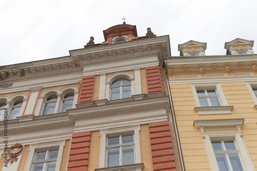 Obraz premium A yellow building that features a striking red roof is situated right next to another building, creating a unique streetscape
