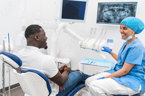 Photos Dental hygienist and African male patient sharing a laugh during a relaxed dental checkup