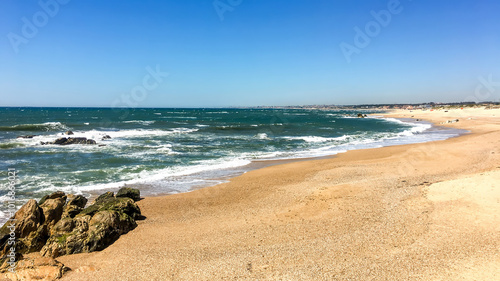 A pristine sandy beach with gentle waves under a clear blue sky, perfect for a summer vacation getaway