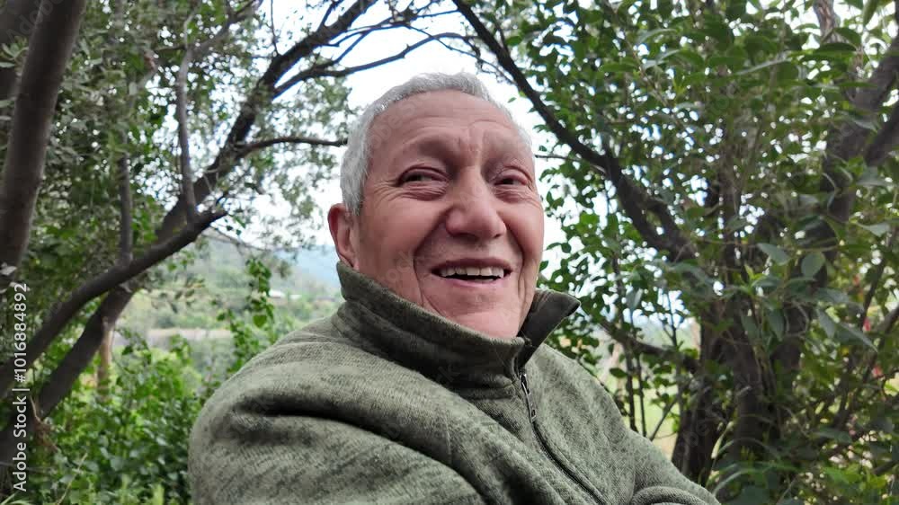 Senior man smiling in a park wearing a hearing aid in his right ear Senior man smiling in a park wearing a hearing aid in his right ear
