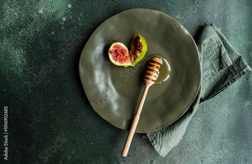 Overhead view of a fresh fig and honey on a plate with a honey dipper photo