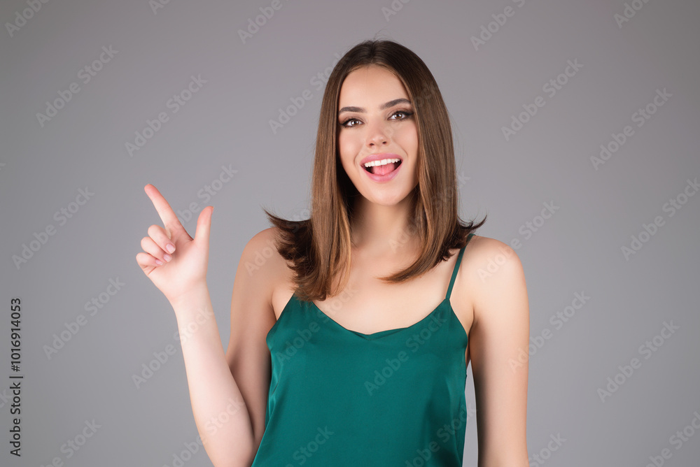 Young woman pointing copy space. Studio portrait of Girl looking at camera and pointing away isolated on gray. Attractive cheerful girl demonstrating copy space ad, web banner. Copy Space. Young woman pointing copy space. Studio portrait of Girl looking at camera and pointing away isolated on gray. Attractive cheerful girl demonstrating copy space ad, web banner. Copy Space.