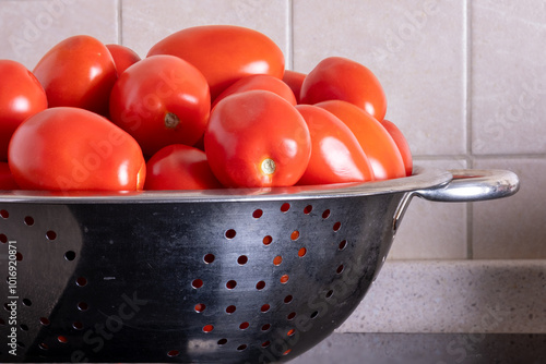 Ripe red tomatoes lying in a metal colander in the kitchen. Home canning. Selective focus.