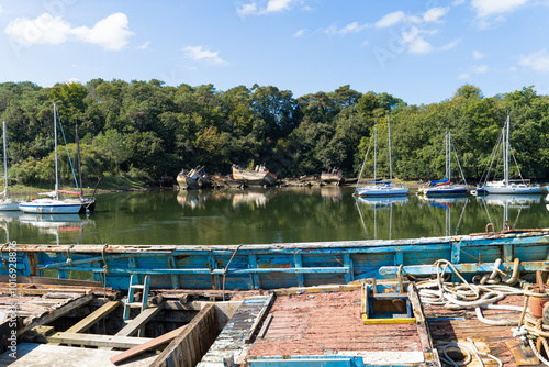Wallpaper Mural Une vue panoramique du cimetière de bateaux à Douarnenez, où les petits bateaux se reflètent dans l'eau, entourés d'épaves et de nuages dans un ciel azur Torontodigital.ca
