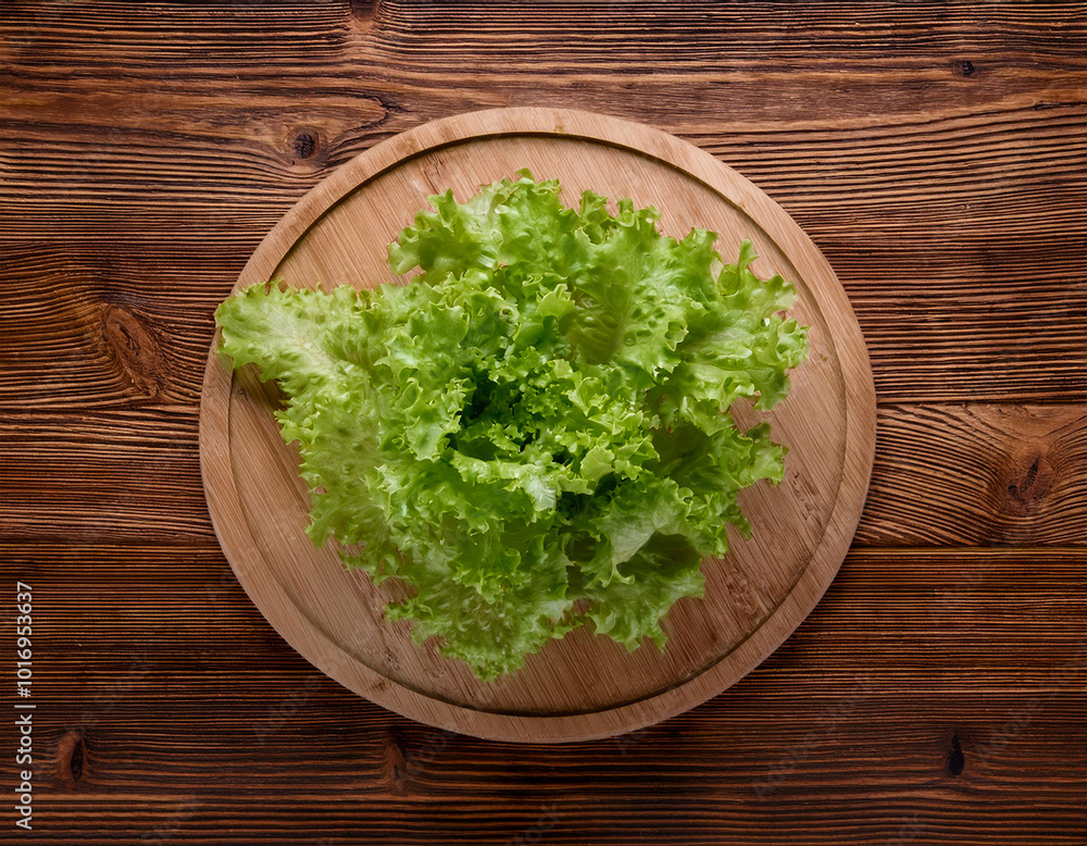 green lettuce on a wooden cutting board, isolated against a wooden background green lettuce on a wooden cutting board, isolated against a wooden background