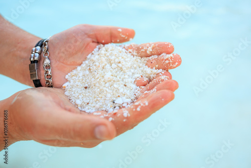 A person is holding a handful of sand in their hand