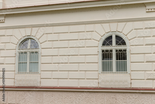 There are two elegantly arched windows positioned on the side of a wellconstructed building, enhancing its overall aesthetic appeal photo