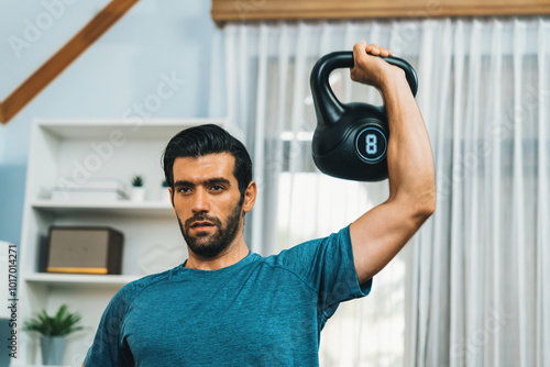 Athletic body and active sporty man lifting kettlebell weight for effective targeting muscle gain at gaiety home as concept of healthy fit body home workout lifestyle. photo