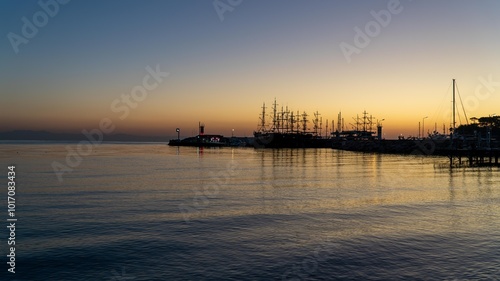 Sunrise at Kemer yacht marina in Antalya, Turkiye. The calm sea reflects the orange sky, capturing the serene beauty of this popular summer vacation spot.