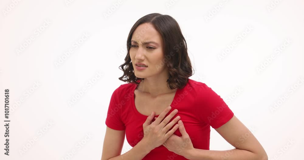 Ill woman touches chest experiencing intense pain on white background. Upset female suffers from painful symptoms due to heart disease Ill woman touches chest experiencing intense pain on white background. Upset female suffers from painful symptoms due to heart disease