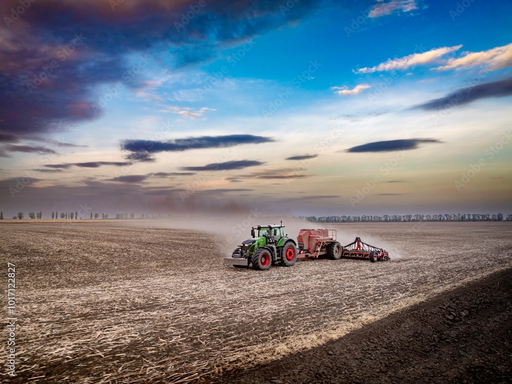modern green tractor sowing wheat seeds in dusty field on sunset with colourful autumn sky modern green tractor sowing wheat seeds in dusty field on sunset with colourful autumn sky