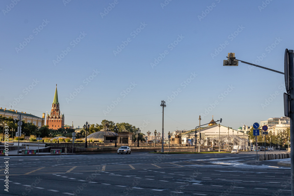 Obraz premium Street in the center of Moscow. A car is driving. Lanterns, traffic lights, road signs. Cloudless sky. The Kremlin in the background. Early morning.