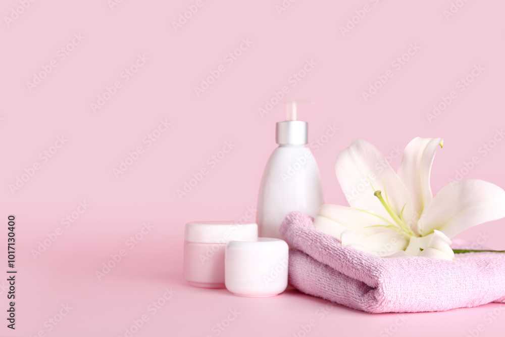 Set of cosmetic products, clean towel and beautiful lily flowers on pink background Set of cosmetic products, clean towel and beautiful lily flowers on pink background
