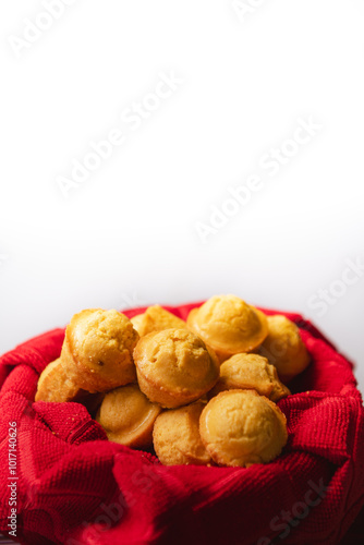 tiny cornbread muffins in a red towel-lined basket in front of a white background photo