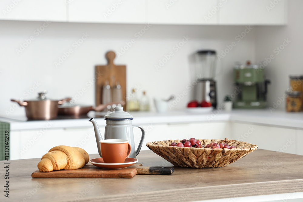 Kitchen table with grapes, cup of tea and croissant in modern kitchen Kitchen table with grapes, cup of tea and croissant in modern kitchen