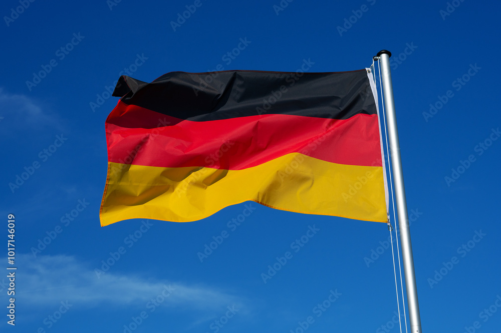 The flag of Germany flutters in the wind against a blue cloudless sky The flag of Germany flutters in the wind against a blue cloudless sky