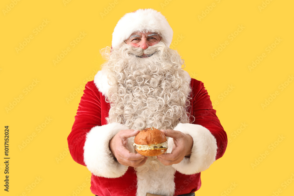Santa Claus with tasty burger on yellow background Santa Claus with tasty burger on yellow background