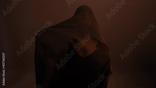 a mystical priestess under a black veil, a woman in black on a dark background, the wind sways the fabric on her face