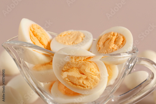 Gravy boat with cut fresh boiled quail eggs on grey background