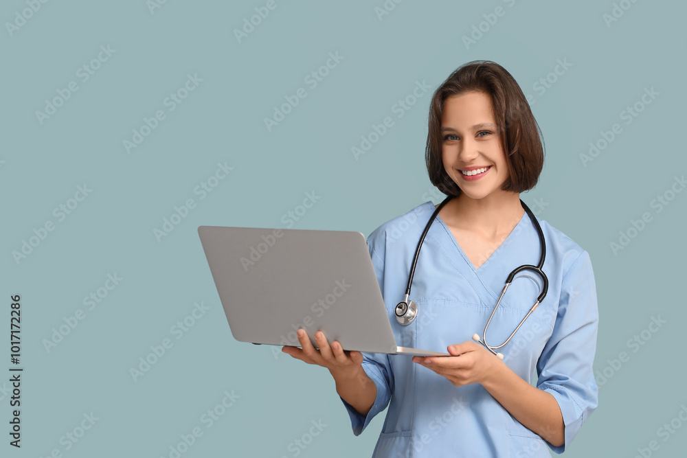 Beautiful female doctor with modern laptop on blue background Beautiful female doctor with modern laptop on blue background