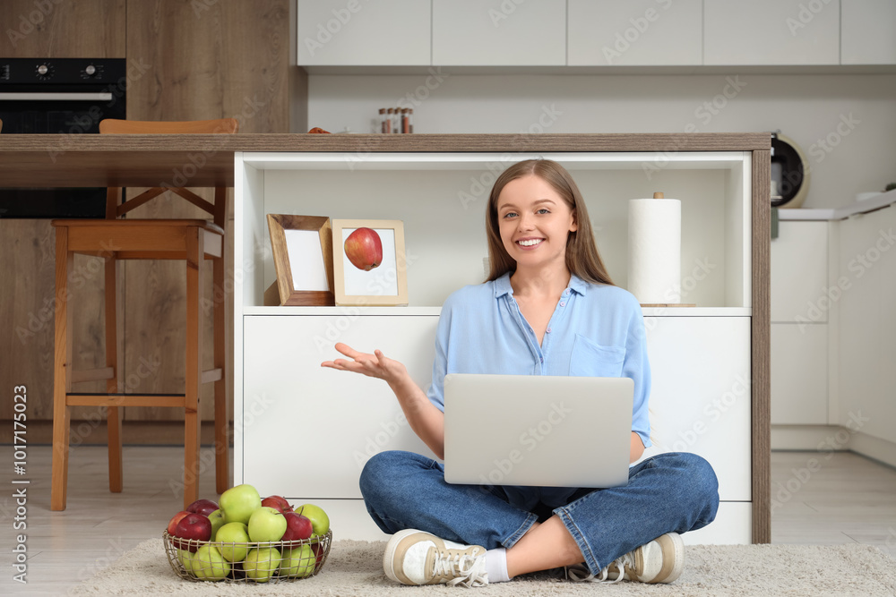 Young woman with laptop tossing apple in kitchen Young woman with laptop tossing apple in kitchen