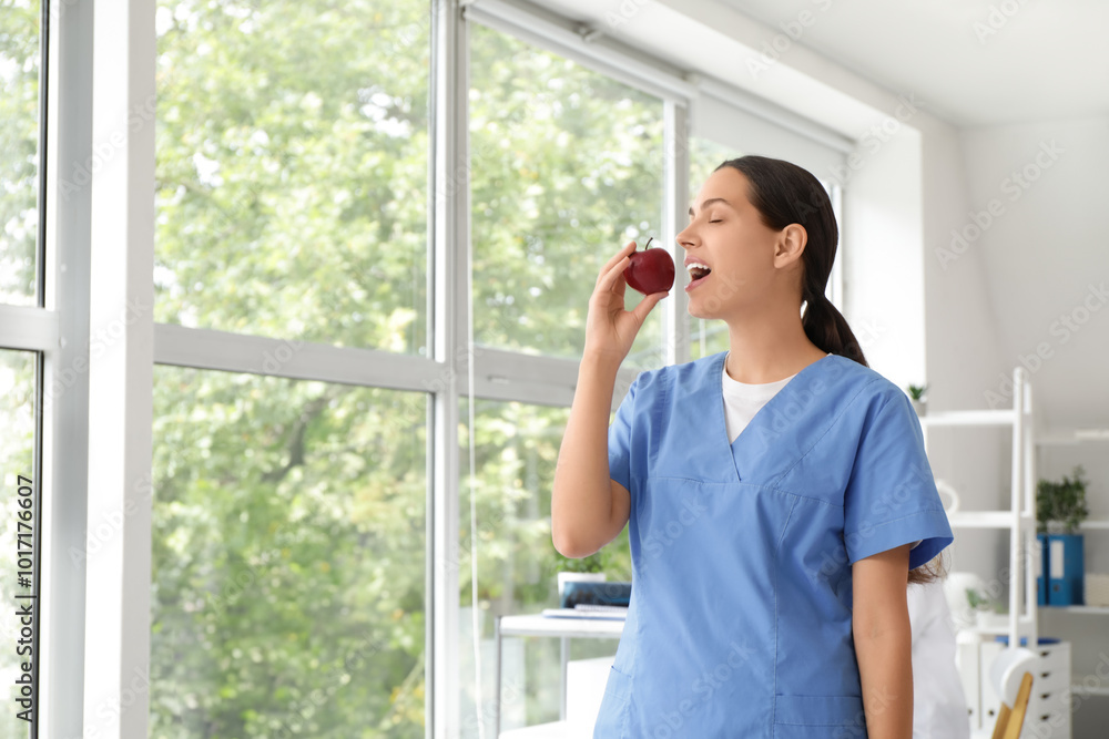 Φωτογραφία Young female doctor eating apple in clinic
