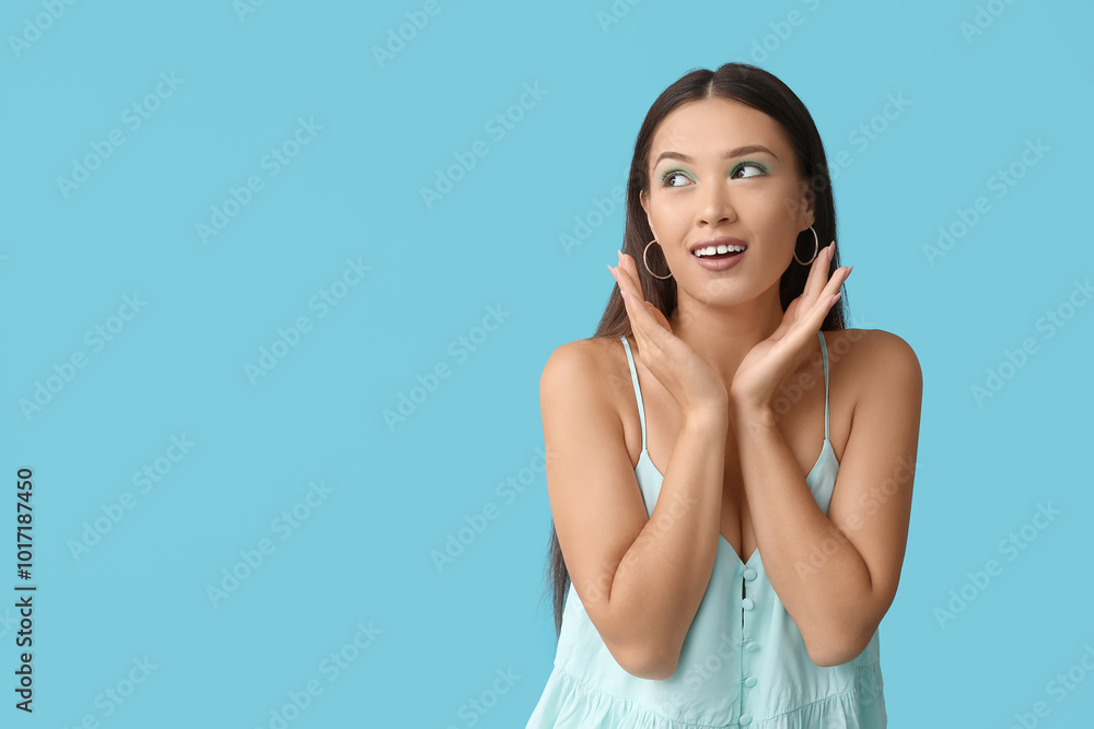 Happy young Asian woman with stylish mint makeup on blue background Happy young Asian woman with stylish mint makeup on blue background