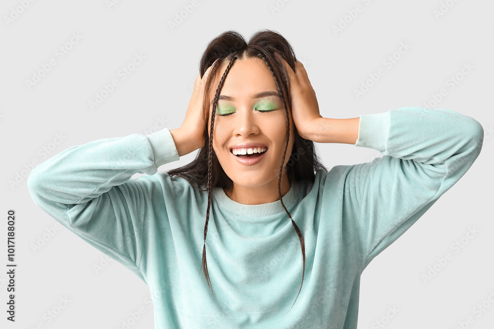 Happy young Asian woman with stylish mint makeup on grey background Happy young Asian woman with stylish mint makeup on grey background