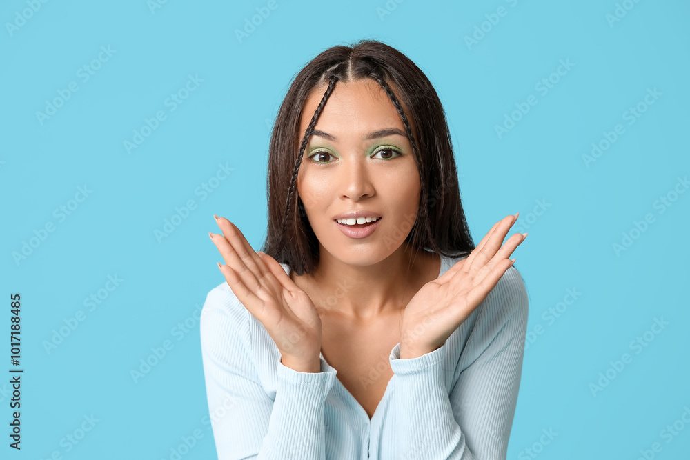Stylish young Asian woman with beautiful mint makeup on blue background Stylish young Asian woman with beautiful mint makeup on blue background
