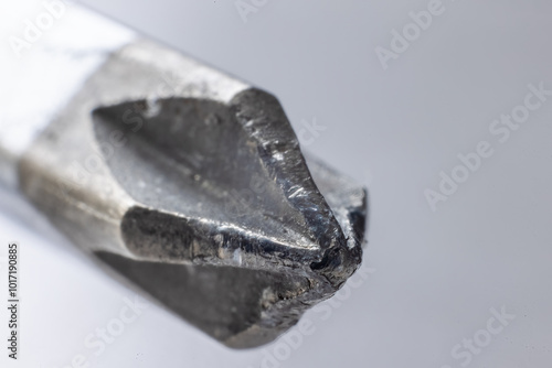 A close-up of a worn, metallic phillips head screwdriver with a flattened tip and visible wear marks.