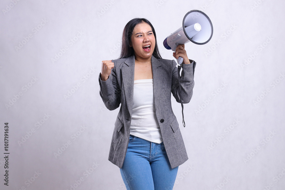 beautiful young female formal angry candid shouting hand holding megaphone loudspeaker and clenched to the side wearing grey suit isolated on white background. fashion concept, announcement, discount beautiful young female formal angry candid shouting hand holding megaphone loudspeaker and clenched to the side wearing grey suit isolated on white background. fashion concept, announcement, discount