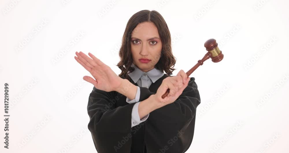 Serious woman judge in black robe holds gavel making Stop gesture on white background. Brunette female demonstrates prohibition in courtoom Serious woman judge in black robe holds gavel making Stop gesture on white background. Brunette female demonstrates prohibition in courtoom