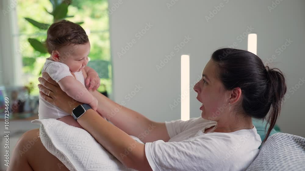 Mother holding up her baby, smiling and engaging in playful interaction, creating a joyful moment of bonding and connection in a cozy home environment Mother holding up her baby, smiling and engaging in playful interaction, creating a joyful moment of bonding and connection in a cozy home environment