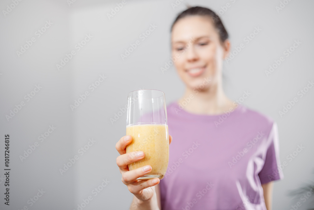 A young woman drinks a vegetable and fruit smoothie in her living room and doing yoga on yoga mat. A young woman drinks a vegetable and fruit smoothie in her living room and doing yoga on yoga mat.