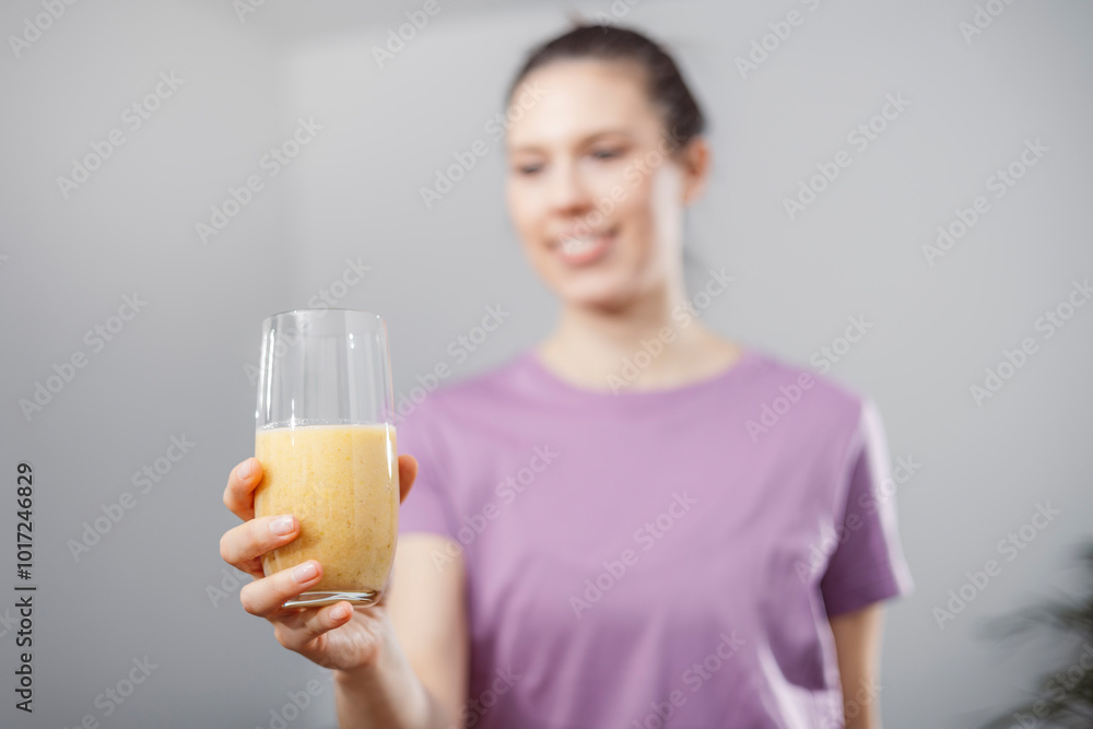 A young woman drinks a vegetable and fruit smoothie in her living room and doing yoga on yoga mat. A young woman drinks a vegetable and fruit smoothie in her living room and doing yoga on yoga mat.