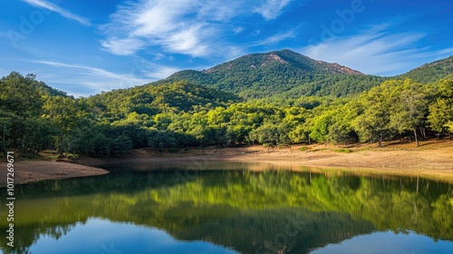 A scenic view of a mountain landscape with a calm reflective lake, green trees, and a vibrant blue sky, ideal for travel and nature photography