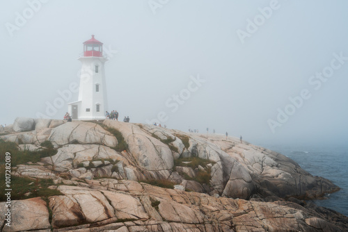 Visitors explore the rocks around Peggy's Cove Lighthouse photo