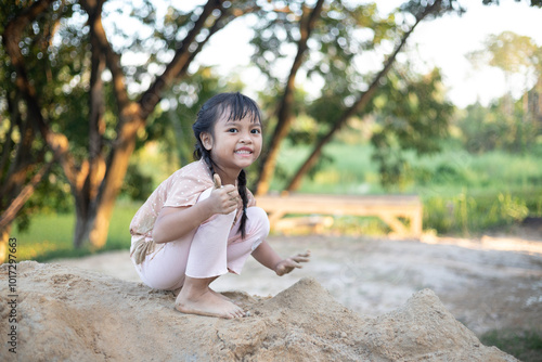 Fototapeta A young girl is playing in the sand