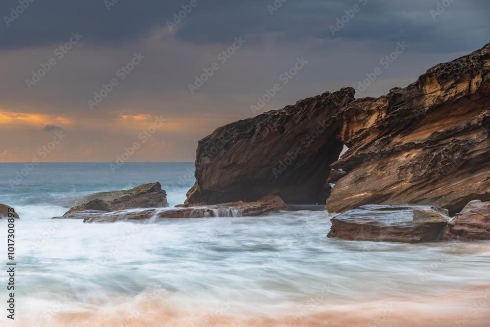 Sunrise at the seaside with rocks and beautiful diffused light by the rain clouds Sunrise at the seaside with rocks and beautiful diffused light by the rain clouds