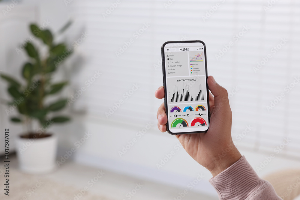 Man monitoring smart meter readings on mobile phone at home, closeup Man monitoring smart meter readings on mobile phone at home, closeup
