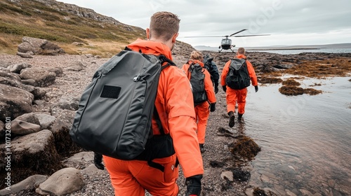 Rescue team in orange suits walking through rocky terrain towards a helicopter. photo