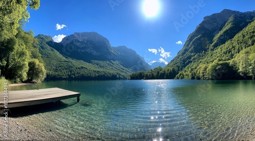 Wooden dock on a clear mountain lake with a bright blue sky and sun shining. photo