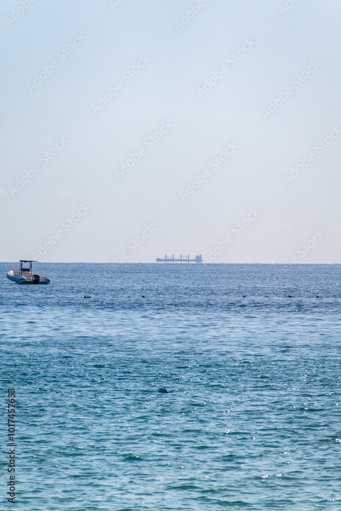 Calm blue sea with the silhouette of a large ship on the horizon Calm blue sea with the silhouette of a large ship on the horizon