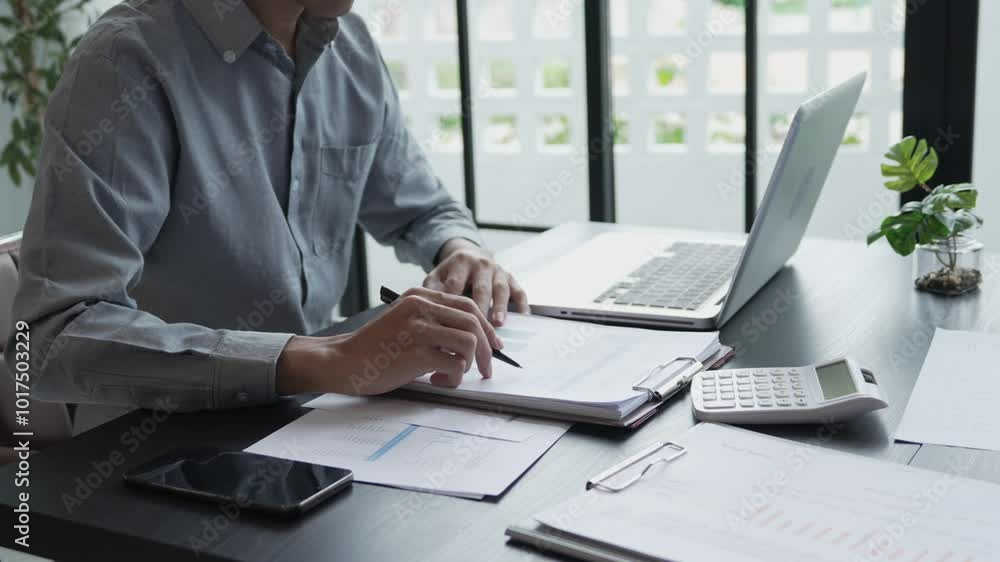 Businessman sits on chair holding pen and checking documents Businessman sits on chair holding pen and checking documents