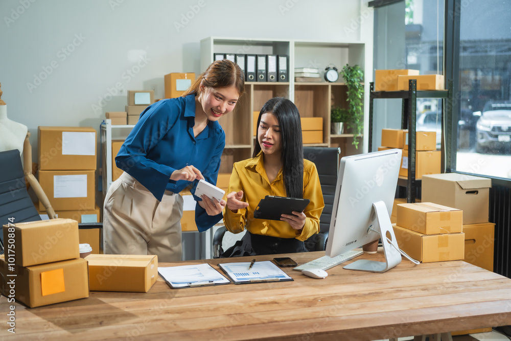 Two Asian business woman work at desk, selling fashion clothes online. They are packing checking items, ready to send to customers. Their clear business planning ensures success in sales marketing Two Asian business woman work at desk, selling fashion clothes online. They are packing checking items, ready to send to customers. Their clear business planning ensures success in sales marketing