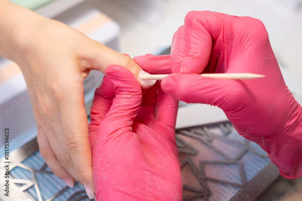 Close up manicure master uses an orange stick to remove cuticula pro clients fingers. Close up manicure master uses an orange stick to remove cuticula pro clients fingers.