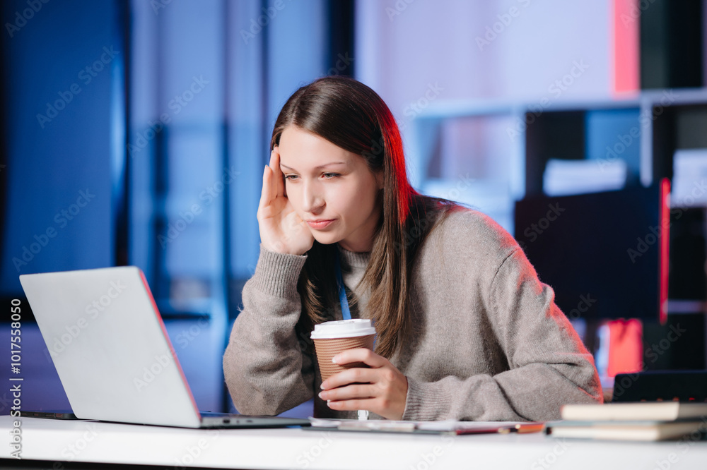 Business woman drinking coffee to get some energy for working overtime sitting at desk using computer and doing overtime project. Business woman drinking coffee to get some energy for working overtime sitting at desk using computer and doing overtime project.