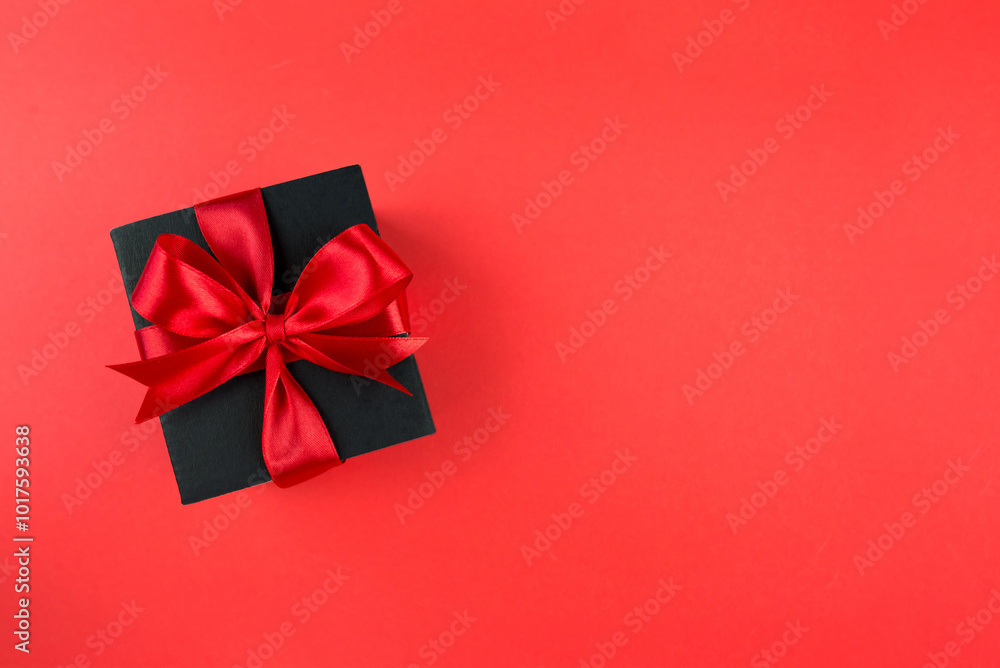 Unwrap savings this Black Friday! Top view of a lavish black gift box tied with a red ribbon, set on a marsala backdrop, providing space for your message or Unwrap savings this Black Friday! Top view of a lavish black gift box tied with a red ribbon, set on a marsala backdrop, providing space for your message or