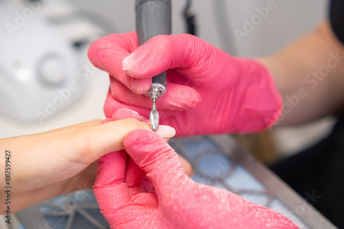 Detail oriented manicure using a nail drill machine at a salon in a well lit environment. photo