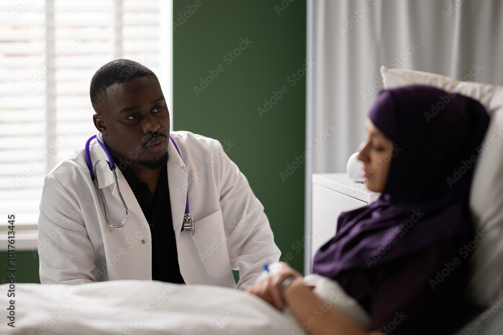 Fototapeta premium Arab patient on the bed and a dedicated African doctor offering care.